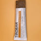 A salted peanut TIROBAR, a vegan and all natural protein bar, is shown half out the wrapper, showing peanuts and bar contents against an orange background. 