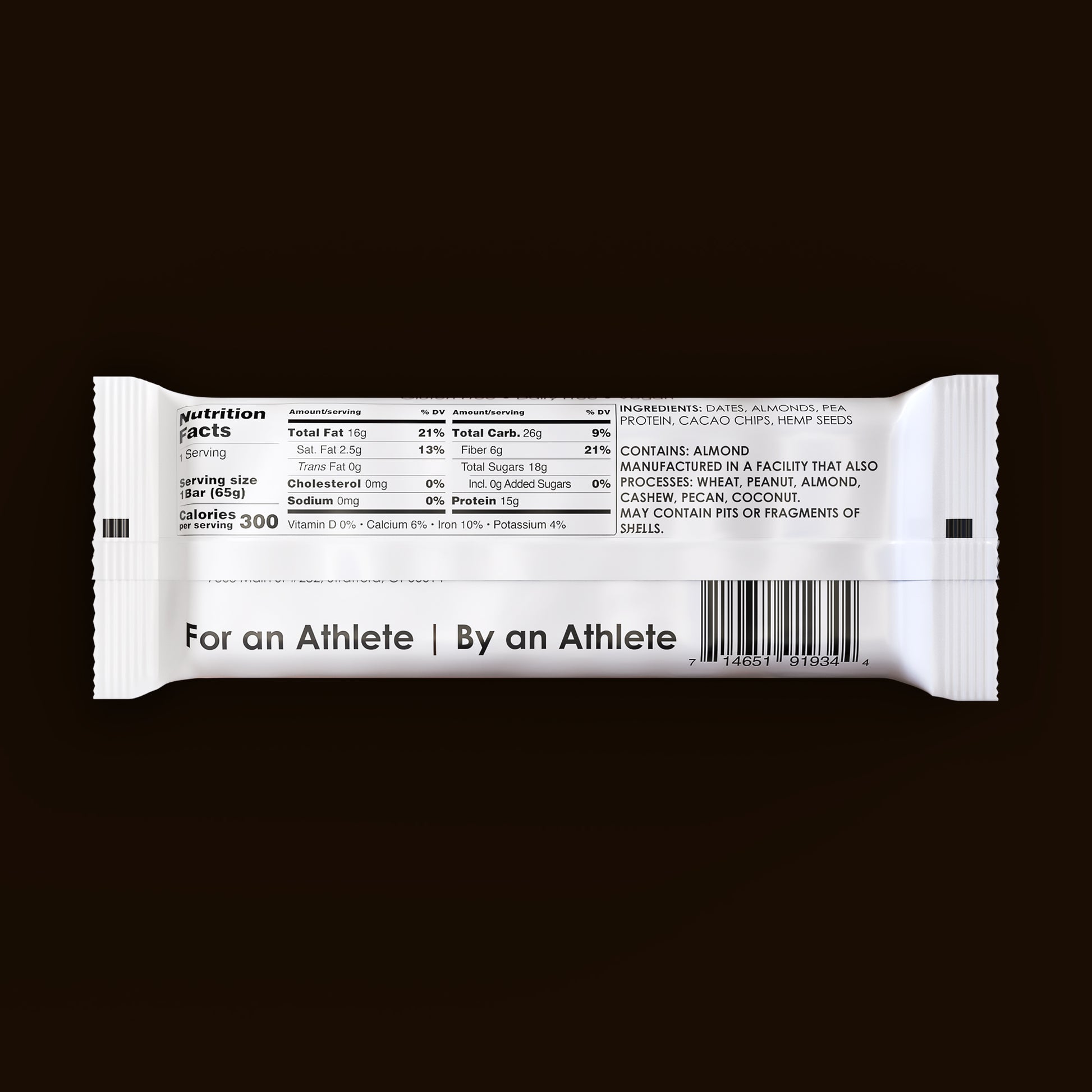 A dark chocolate chip TIROBAR, a vegan and all natural protein bar, sits in a white wrapper against a brown background. The bar is visible from the top with a view of the nutrition facts.